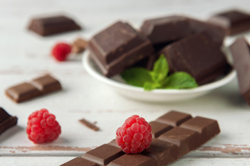 Raspberry, pieces of chocolate, chocolate shavings and mint on white Provence style table.