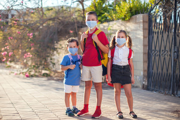 Obraz premium Pupils with medical masks on face and backpacks outdoor. Education during coronavirus time. Back to school.
