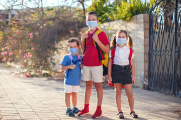 Pupils with medical masks on face and backpacks outdoor. Education during coronavirus time. Back to school.