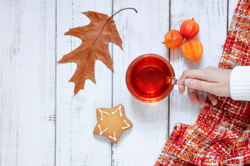 autumn layout with fallen leaves, a cup of tea and a warm knitted scarf, autumn weekend, home comfort