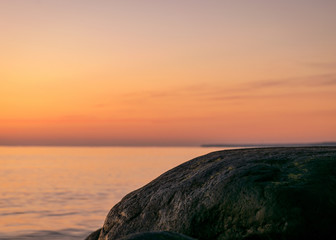 orange sunset by the sea, black stone silhouettes against the sea background, summer