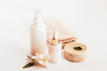 Cosmetic soap, serum and tonic bottles in white blank packages with jasmine blossom, white...