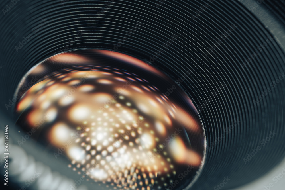 Aufkleber beautiful camera lens on a dark with yellow shine reflection light background. macro view.