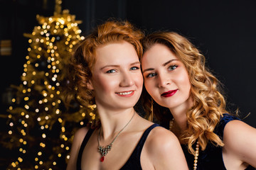 Two beautiful girls with bokeh lights Christmas garland. Gold Christmas decoration. Happy new year.