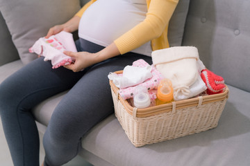 Asian pregnant woman smile and sitting on the sofa with feeling happy and relaxed.