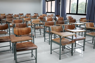 Empty school classroom with many wooden chairs. Wooden chairs in classroom. Empty classroom with vintage tone wooden chairs. Empty college classroom. Education stock photo.