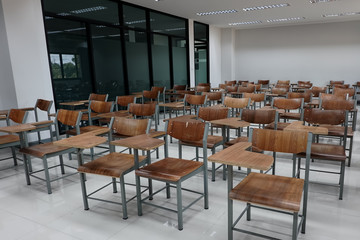 Fototapeta na wymiar Empty school classroom with many wooden chairs. Wooden chairs in classroom. Empty classroom with vintage tone wooden chairs. Empty college classroom. Education stock photo.