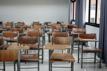 Empty school classroom with many wooden chairs. Wooden chairs in classroom. Empty classroom with vintage tone wooden chairs. Empty college classroom. Education stock photo.