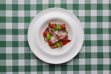 Meat in sweet and sour sauce with strawberries. Served in a white plate over green plaid tablecloth.