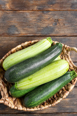 Raw zucchini. Zucchini and zucchini in a basket on a brown wooden table. Top view with space for text