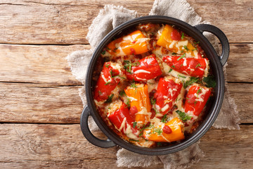Homemade hearty baked stuffed peppers with tomato sauce and cheese close-up in a frying pan on the table. horizontal top view from above