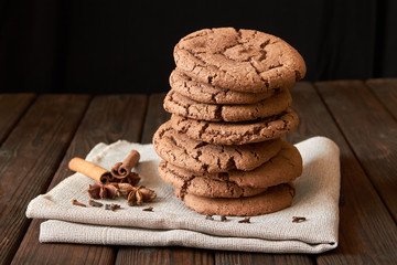 Stacked cookies with spices on brown napkin and on wooden table