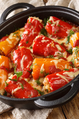 Stuffed peppers with rice and meat baked with cheese and tomatoes close-up in a pan on the table. vertical