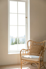 a rattan chair by the window through which the bright morning light shines.