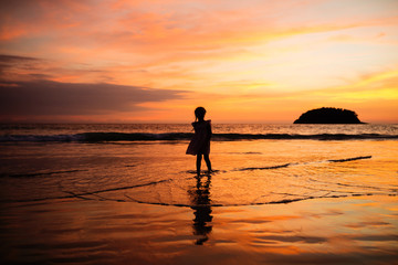 Fototapeta na wymiar Happy child girl black silhouette on sun background. Kid having fun by water pool along sea on beach. Travel lifestyle, summer vacation.
