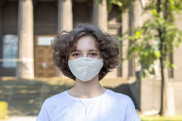 Young woman in a protective mask on the background of a old city street.