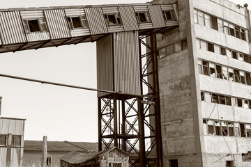 Old, abandoned concrete plant with iron rusty tanks and metal structures. The crisis, the fall of the economy, stop production capacity led to the collapse. Global catastrophe. Old photo effect