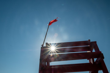 Rescue tower by the sea. Red observation post near the water. Signal, red flag. The wind flutters...