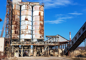 Old, abandoned concrete plant with iron rusty tanks and metal structures. The crisis, the fall of the economy, stop production capacity led to the collapse. Global catastrophe.