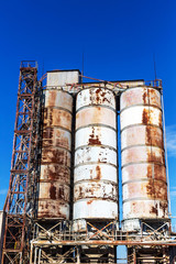 Old, abandoned concrete plant with iron rusty tanks and metal structures. The crisis, the fall of the economy, stop production capacity led to the collapse. Global catastrophe.