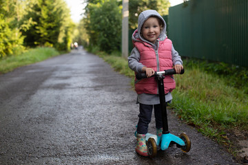 Pretty toddler girl with scooter in the coutryside