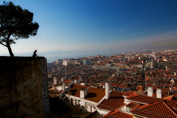 Lisbon panoramic view with red roofs and male silhouette on viewing observation point