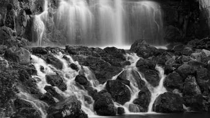 Black and white water gushing over rocks at a waterfall