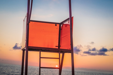 Rescue tower by the sea. Red observation post near the water. Signal, red flag. The wind flutters...