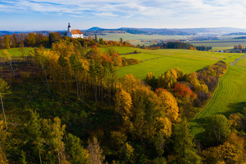 Scenic autumn landscape with small Roman Catholic church on hilltop, Czech Republic..