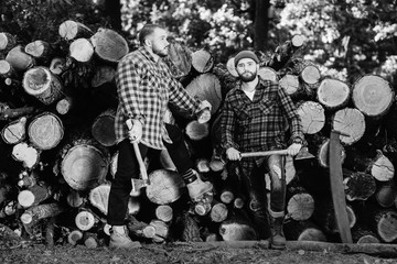 Two bearded brutal woodcutters with hand saw and ax