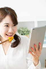 タブレットPCを見ながら食事する女性 © Paylessimages