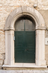 Fototapeta na wymiar External daytime photo of a recent iron door carved out of a medieval carved stone decorated door in Venosa in the Basilicata region of southern Italy