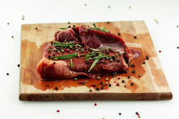 beef steak on a wooden Board, seasoned with pepper and rosemary
