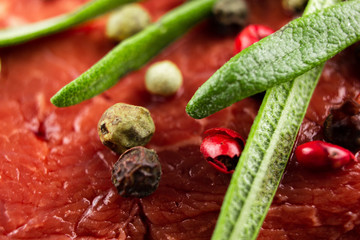 raw beef steak with vegetables, seasoned with pepper and rosemary, close-up