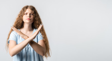 Young woman shows a STOP gesture on white background