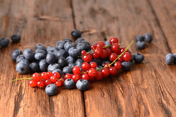 Fresh red currants and blueberries on the wooden table.