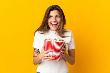 Young slovak woman isolated on yellow background holding a big bucket of popcorns