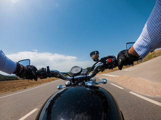 Driving an old black motorcycle driver point of view on a summer landscape solid blue sky