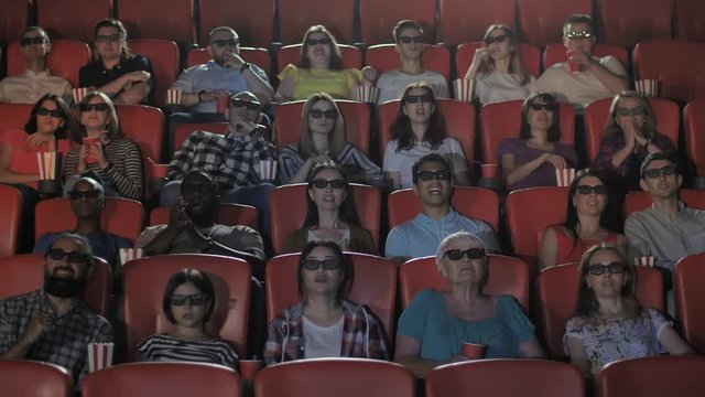 Multinational groups, couples and friends watching movie show wearing 3d glasses. Multi-ethnic audience excitedly watching 3d movie, chatting, drinking soda, eating popcorn