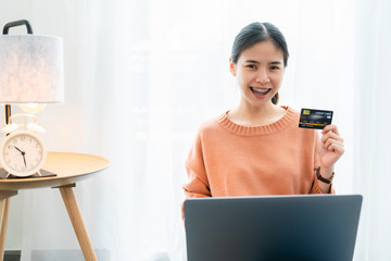 Beautiful Asian woman holding credit card and using digital laptop with shopping online for banner size with copy space advertisement background.