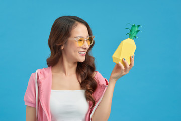 Attractive happy young woman holding fresh pineapple with a smile.