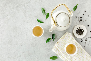 Herbal tea with two white tea cups and teapot, with green tea leaves. Flat lay, top view. Tea concept