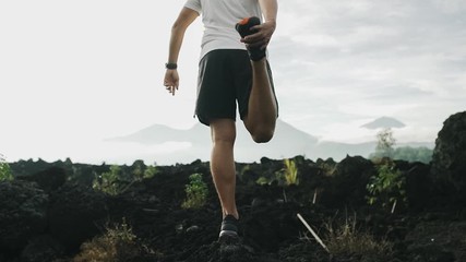 Man doing stretching and preparing for workout and running outdoors. Mountain view on background. Healthy lifestyle concept