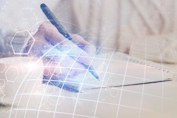 Double exposure of hands making notes with world map hologram and data theme icons. Concept of global computer data.