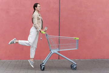 Charming girl shopping. Girl with a cart near the store