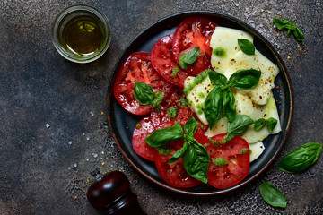 Caprese - traditional italian tomato salad with mozzarella cheese and basil. Top view with copy space.