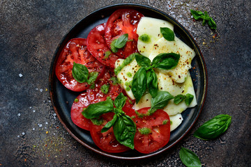 Caprese - traditional italian tomato salad with mozzarella cheese and basil. Top view with copy space.