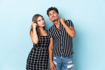 Teenager caucasian couple isolated on blue background thinking an idea while scratching head