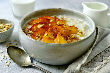 Delicious oat porridge with caramelized peaches and nuts for a breakfast.