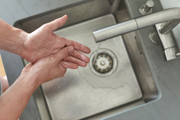 Mann wäscht sich am Waschbecken die Hände mit Seife